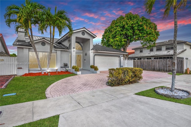 view of front of home with a lawn, a garage, fence, stucco siding, and decorative driveway