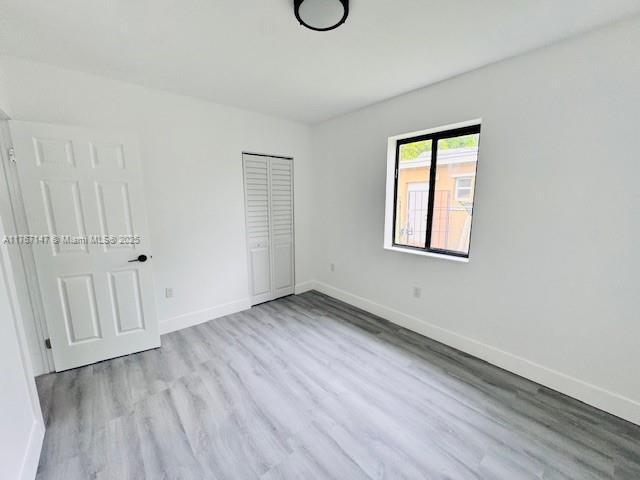 11730 NW 3rd Ave, Miami, FL 33168 - unfurnished bedroom featuring wood finished floors, baseboards, and a closet