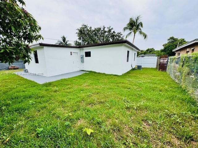 11730 NW 3rd Ave, Miami, FL 33168 - rear view of house featuring a yard, central AC unit, stucco siding, and fence