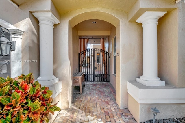 doorway to property with stucco siding and a gate