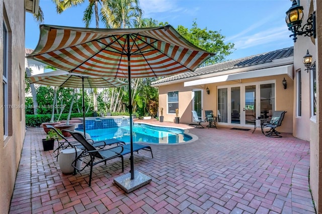 view of swimming pool with french doors, a pool with connected hot tub, and a patio area
