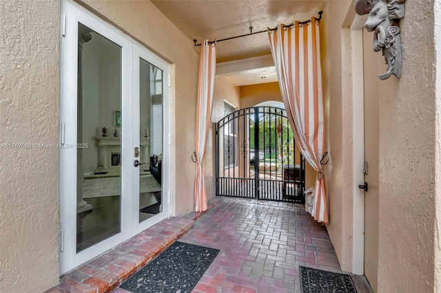 entrance to property with a gate, french doors, and stucco siding