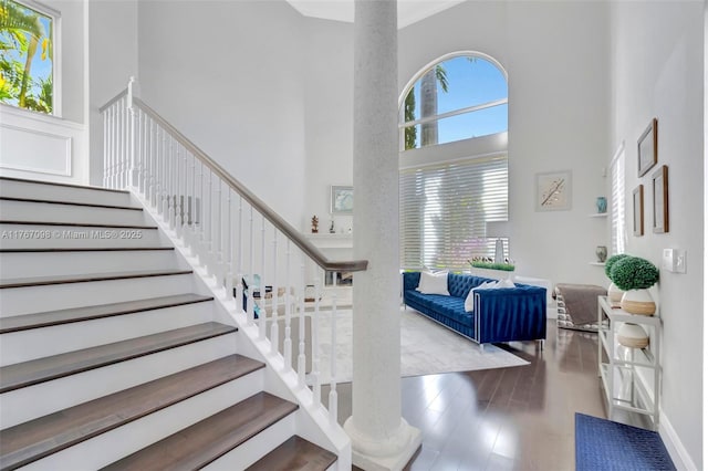 stairs featuring wood finished floors and a towering ceiling