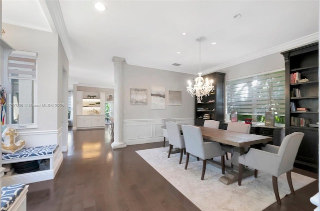 dining space with dark wood finished floors, a chandelier, ornamental molding, wainscoting, and a decorative wall