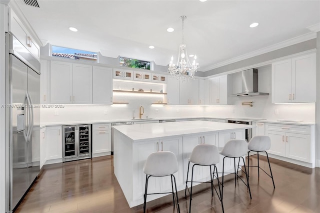 kitchen with beverage cooler, stainless steel built in refrigerator, a kitchen breakfast bar, white cabinetry, and wall chimney exhaust hood