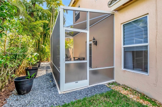 view of side of home featuring stucco siding and glass enclosure