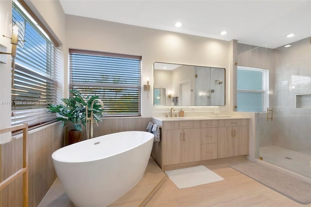 full bathroom with double vanity, recessed lighting, a stall shower, a freestanding bath, and a sink