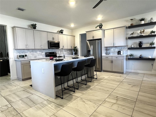 17731 SW 295th St, Homestead, FL 33030 - kitchen with marble finish floor, a breakfast bar, gray cabinetry, appliances with stainless steel finishes, and light countertops