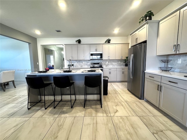 17731 SW 295th St, Homestead, FL 33030 - kitchen featuring visible vents, a breakfast bar, gray cabinets, light countertops, and appliances with stainless steel finishes