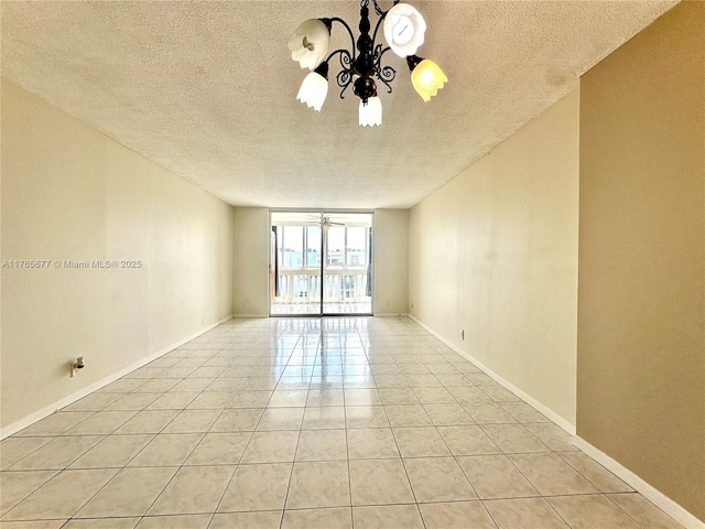 spare room with ceiling fan with notable chandelier, baseboards, a textured ceiling, and light tile patterned floors