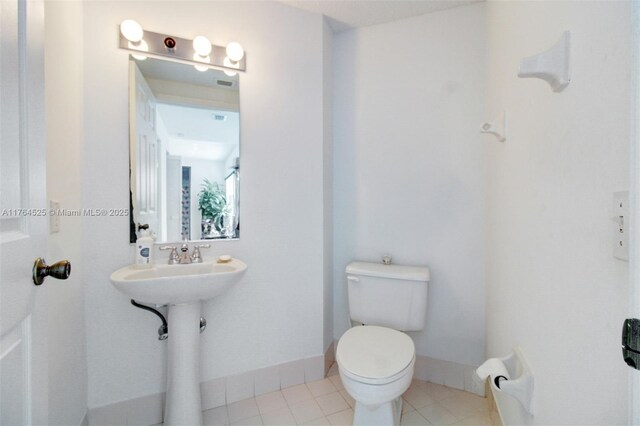 bathroom featuring toilet, baseboards, and tile patterned flooring
