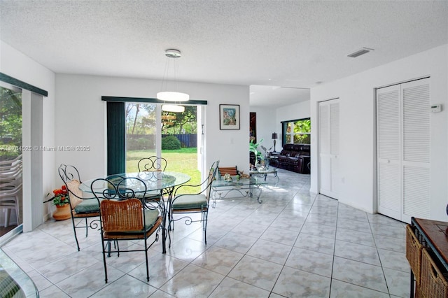 dining space with visible vents, a textured ceiling, and light tile patterned flooring