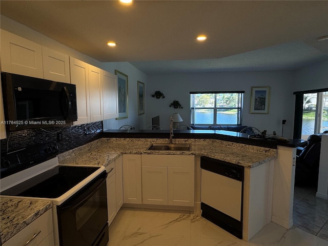 kitchen featuring black microwave, dishwasher, a sink, a peninsula, and electric stove