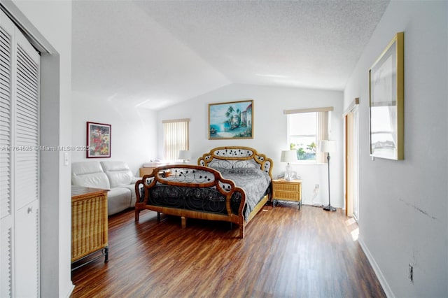 bedroom with baseboards, wood finished floors, lofted ceiling, and a closet