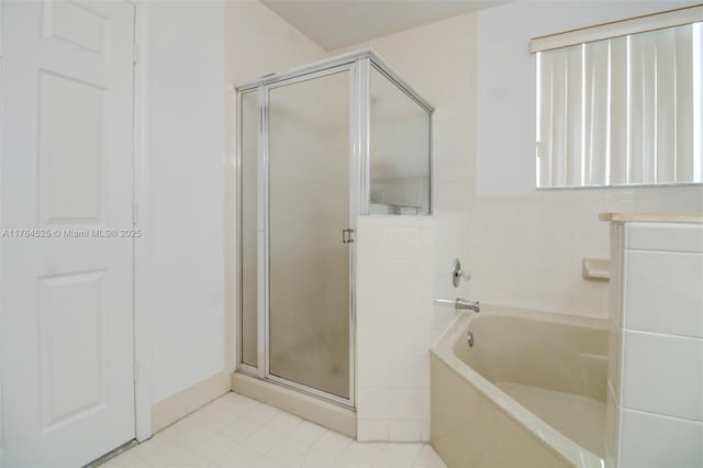 bathroom featuring tile patterned flooring, a shower stall, and a bath