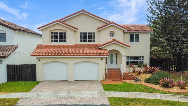 mediterranean / spanish-style house with a garage, stucco siding, driveway, and a tile roof