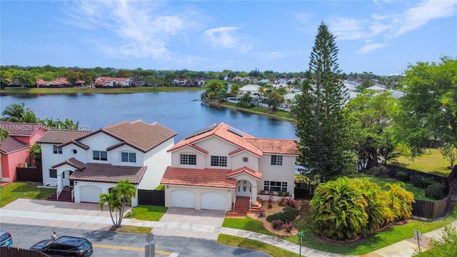 view of front of house with a garage, fence, a water view, and a tile roof