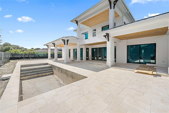 rear view of property featuring a patio area, fence, and stucco siding