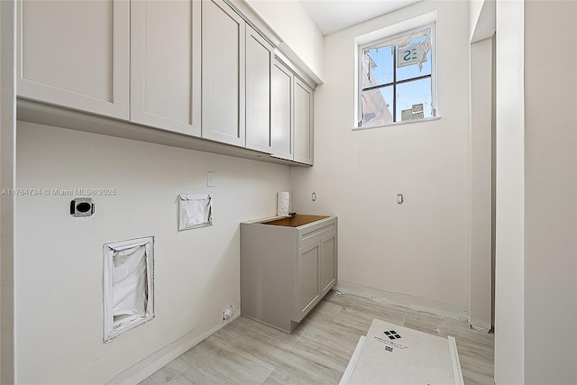 laundry room featuring electric dryer hookup, cabinet space, light wood-style floors, and baseboards