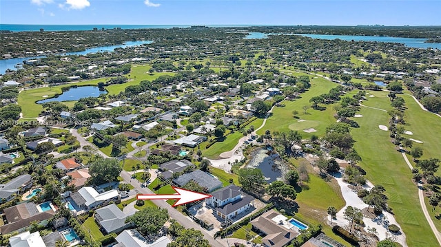 view of property location featuring a nearby body of water, nearby suburban area, and a golf course