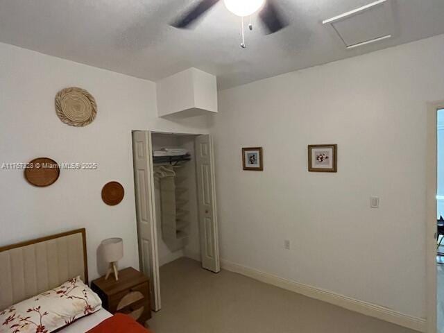 bedroom featuring a closet, light colored carpet, attic access, and ceiling fan