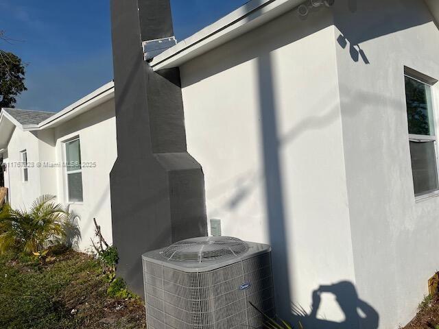 view of side of property with central AC unit and stucco siding