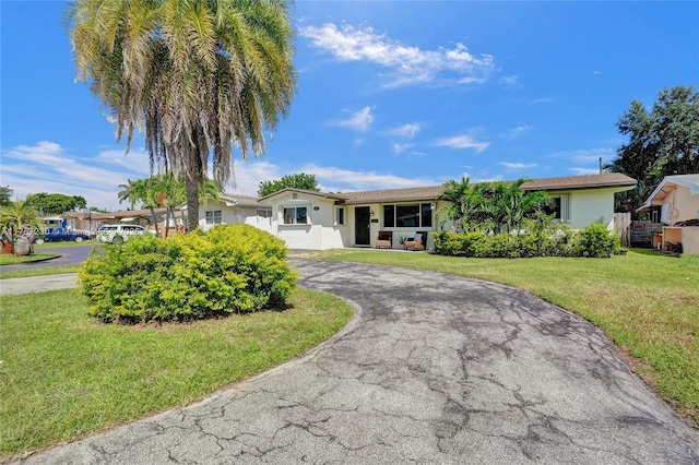 ranch-style house with curved driveway and a front lawn