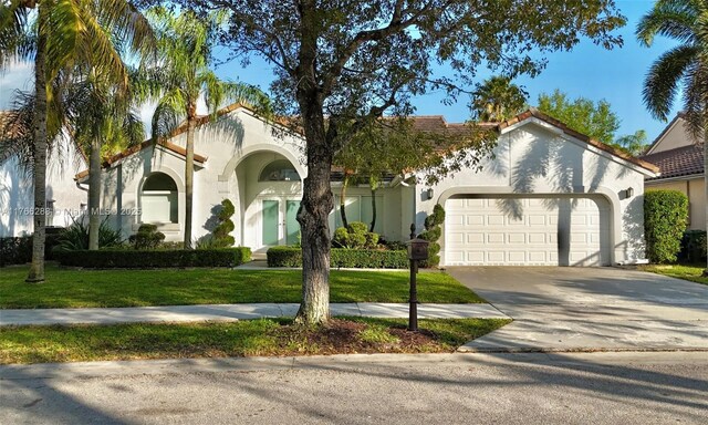 710 Lake Blvd, Weston, FL 33326 - mediterranean / spanish house featuring a garage, stucco siding, concrete driveway, and a front yard