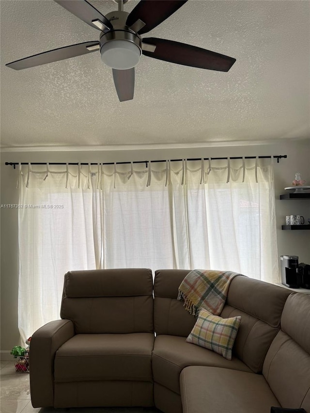 living room with a textured ceiling and ceiling fan