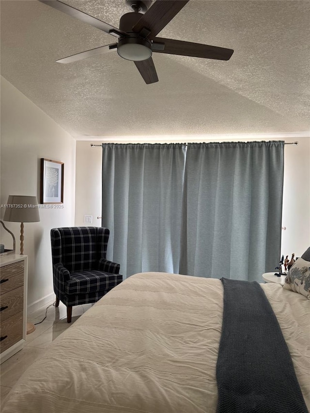 bedroom with a textured ceiling, light marble finish flooring, and a ceiling fan