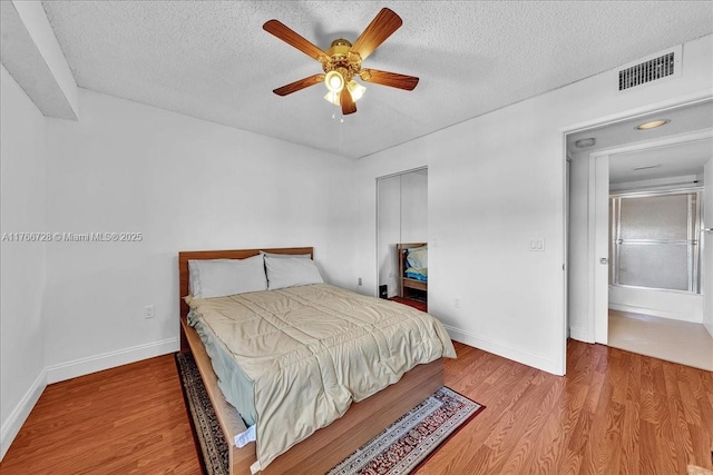 bedroom featuring wood finished floors, a textured ceiling, baseboards, a closet, and a ceiling fan