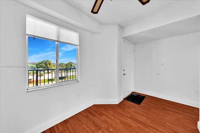 unfurnished room featuring baseboards, wood finished floors, a ceiling fan, and a textured ceiling