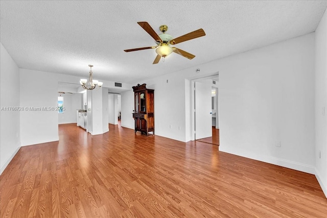 unfurnished living room featuring ceiling fan, a chandelier, a textured ceiling, light wood-style flooring, and baseboards
