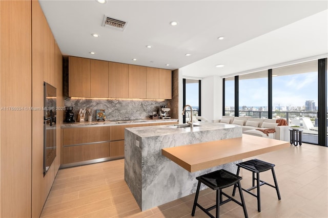 500 Alton Rd Unit 1201, Miami Beach, FL 33139 - kitchen featuring tasteful backsplash, a kitchen island with sink, a kitchen bar, a sink, and modern cabinets
