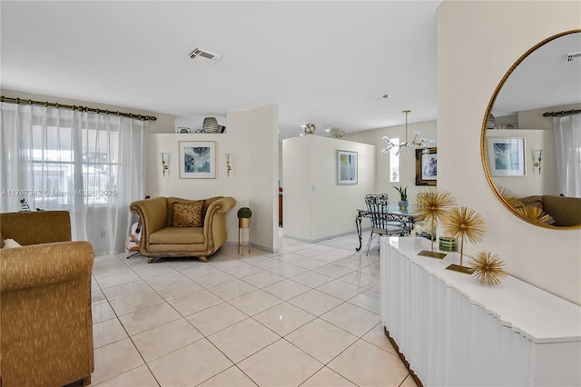 living area with light tile patterned floors, plenty of natural light, an inviting chandelier, and visible vents