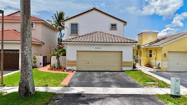 mediterranean / spanish-style house with stucco siding, a tiled roof, and aphalt driveway