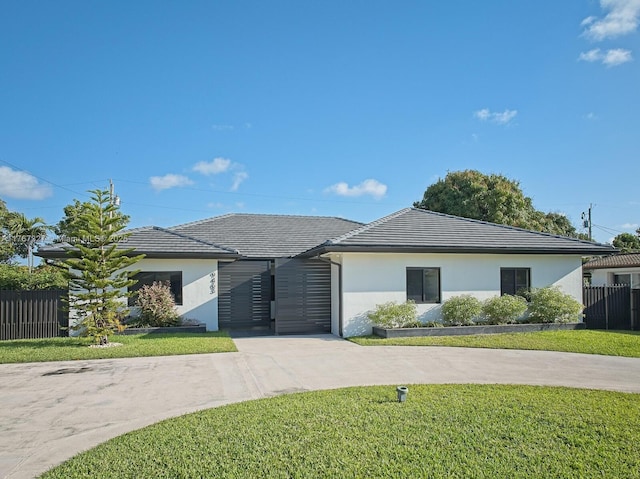 ranch-style house with a front yard, a tiled roof, driveway, and stucco siding