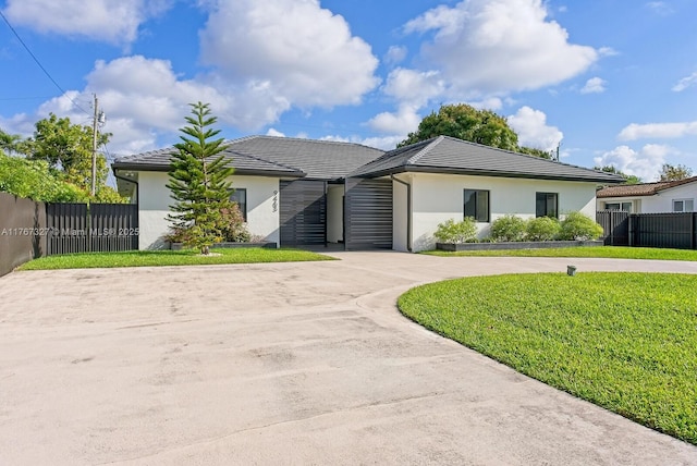 view of front facade featuring a front yard, curved driveway, fence, and stucco siding