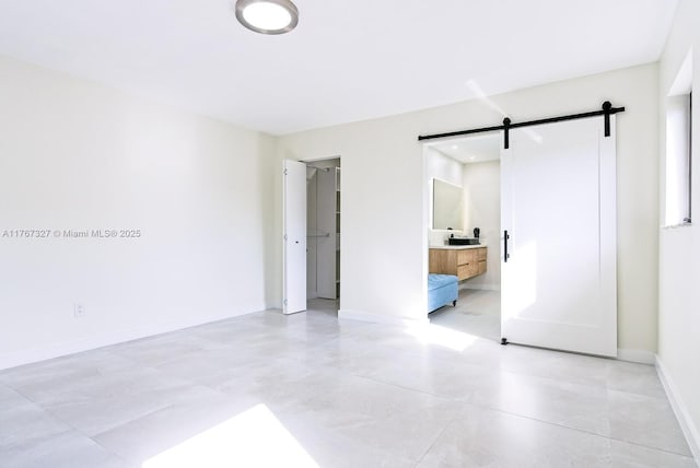 unfurnished bedroom featuring baseboards and a barn door