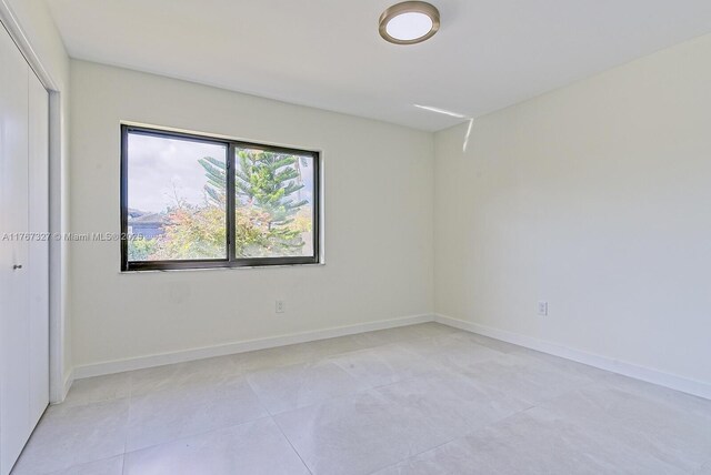 unfurnished room featuring light tile patterned flooring and baseboards