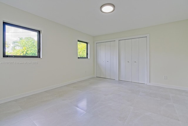 unfurnished bedroom featuring baseboards and multiple closets