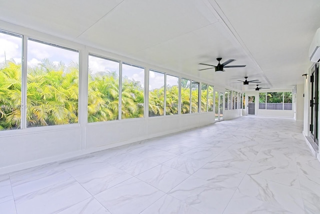 unfurnished sunroom with a ceiling fan, marble finish floor, and a wall mounted air conditioner