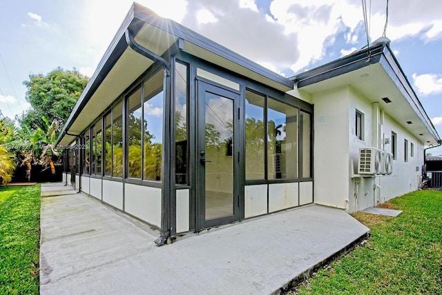 view of side of home featuring a yard, stucco siding, central AC, and a sunroom