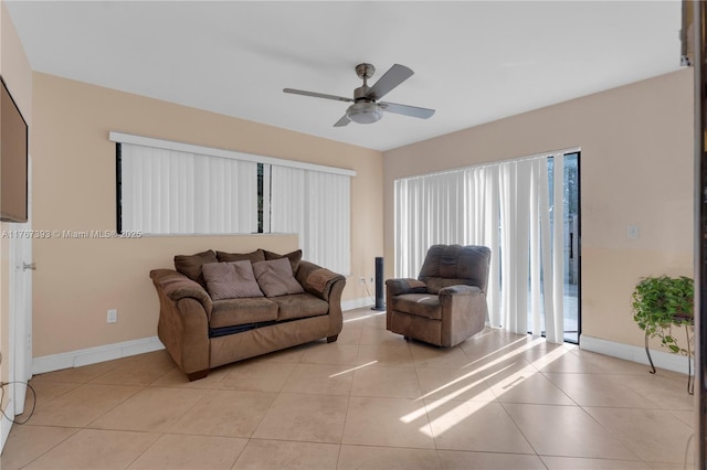 living area featuring light tile patterned floors, baseboards, and ceiling fan