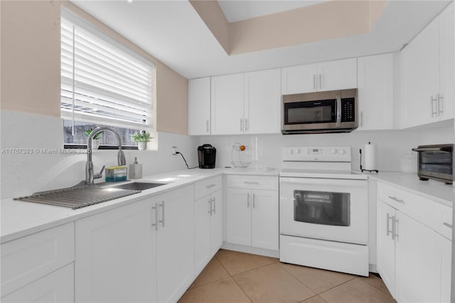 kitchen featuring light tile patterned floors, stainless steel microwave, white cabinets, and white electric range
