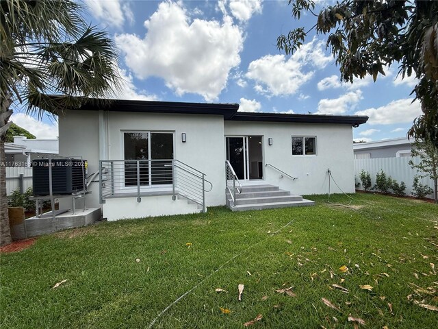 3431 NW 14th Ter, Miami, FL 33125 - rear view of house featuring stucco siding, fence, a lawn, and central AC