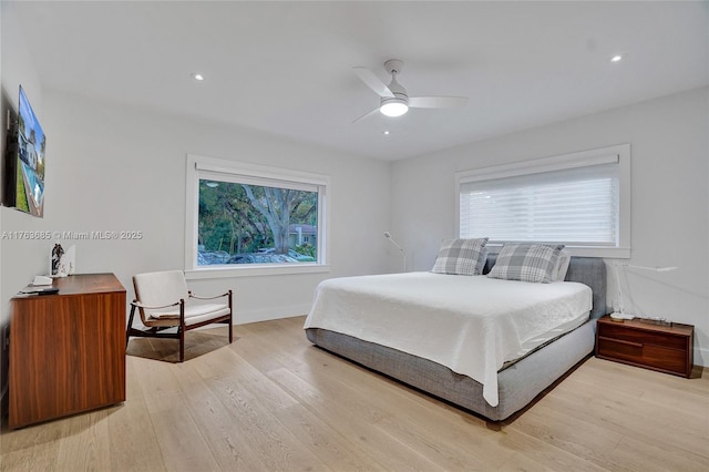 bedroom featuring light wood finished floors, multiple windows, baseboards, and a ceiling fan