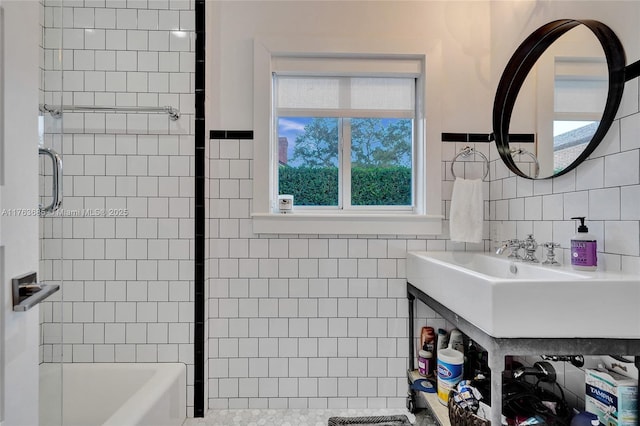 bathroom with a wealth of natural light, shower / tub combination, tile walls, and a sink
