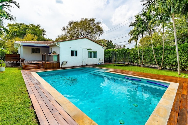 view of pool with a trampoline, a fenced in pool, a yard, and a wooden deck