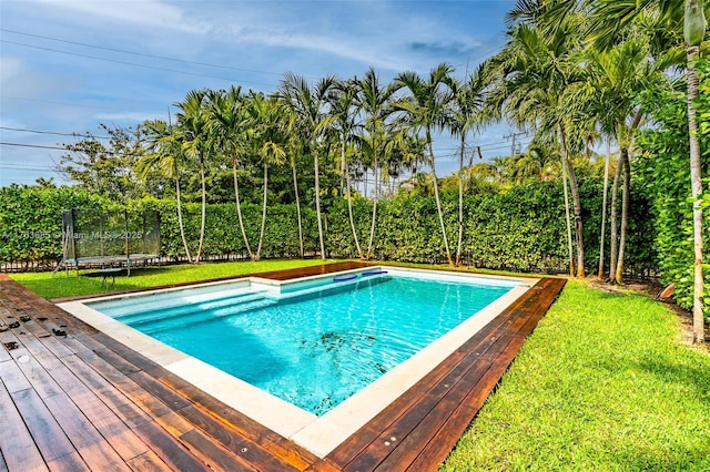view of swimming pool featuring a trampoline, a fenced in pool, a deck, and a yard